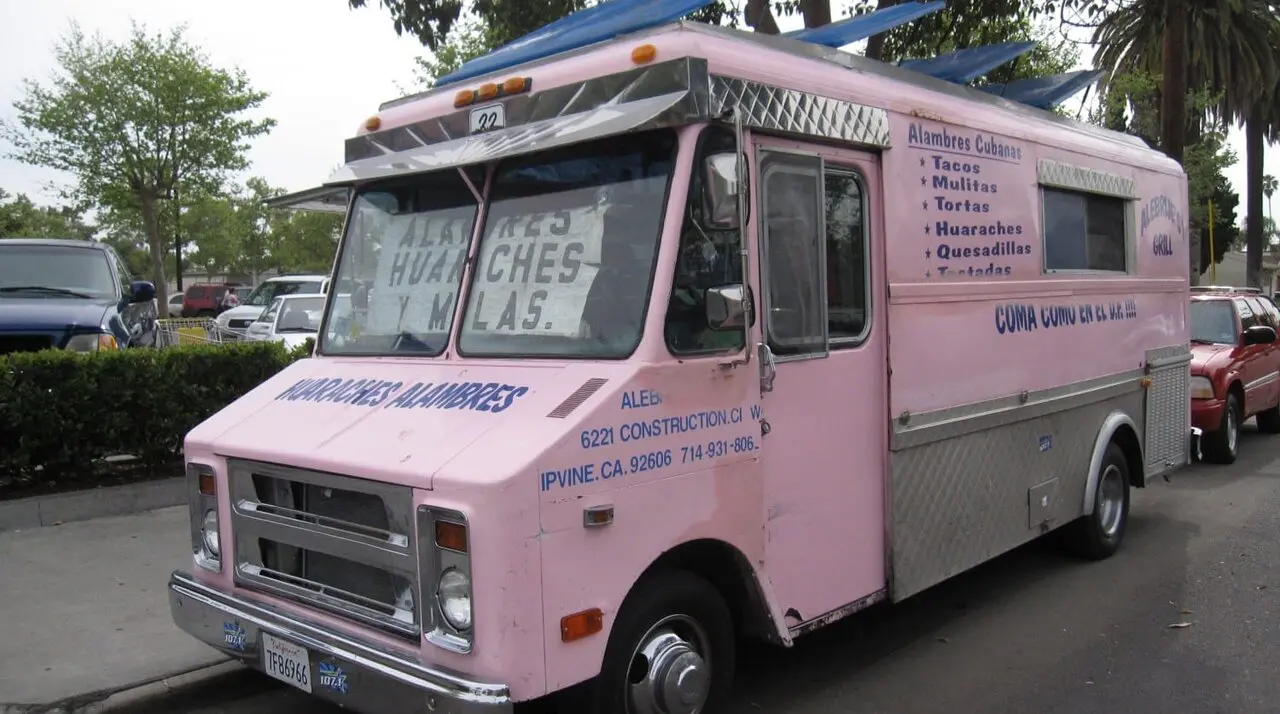 Pink and purple Alebrijes Grill taco truck in Santa Ana with a taco acorazado on the window ledge