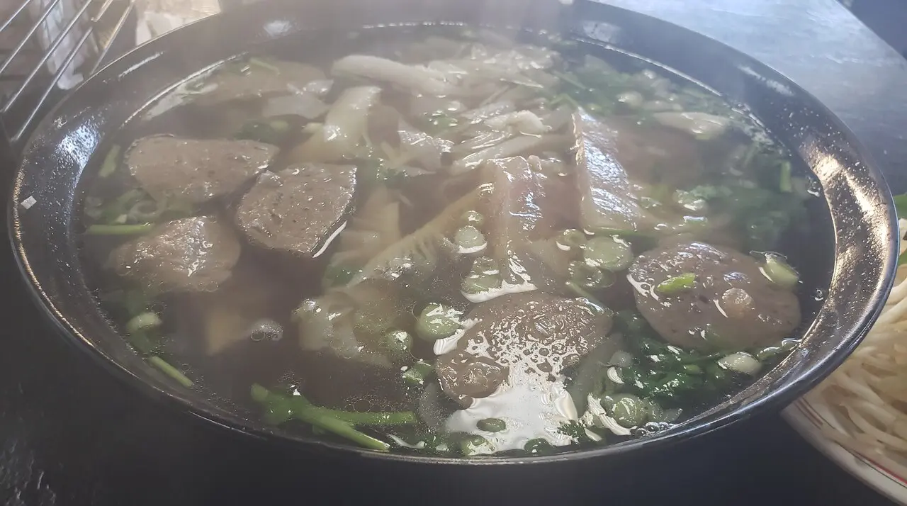 Steaming bowl of beef pho with meatballs, brisket, and herbs at Pho 79 in Little Saigon