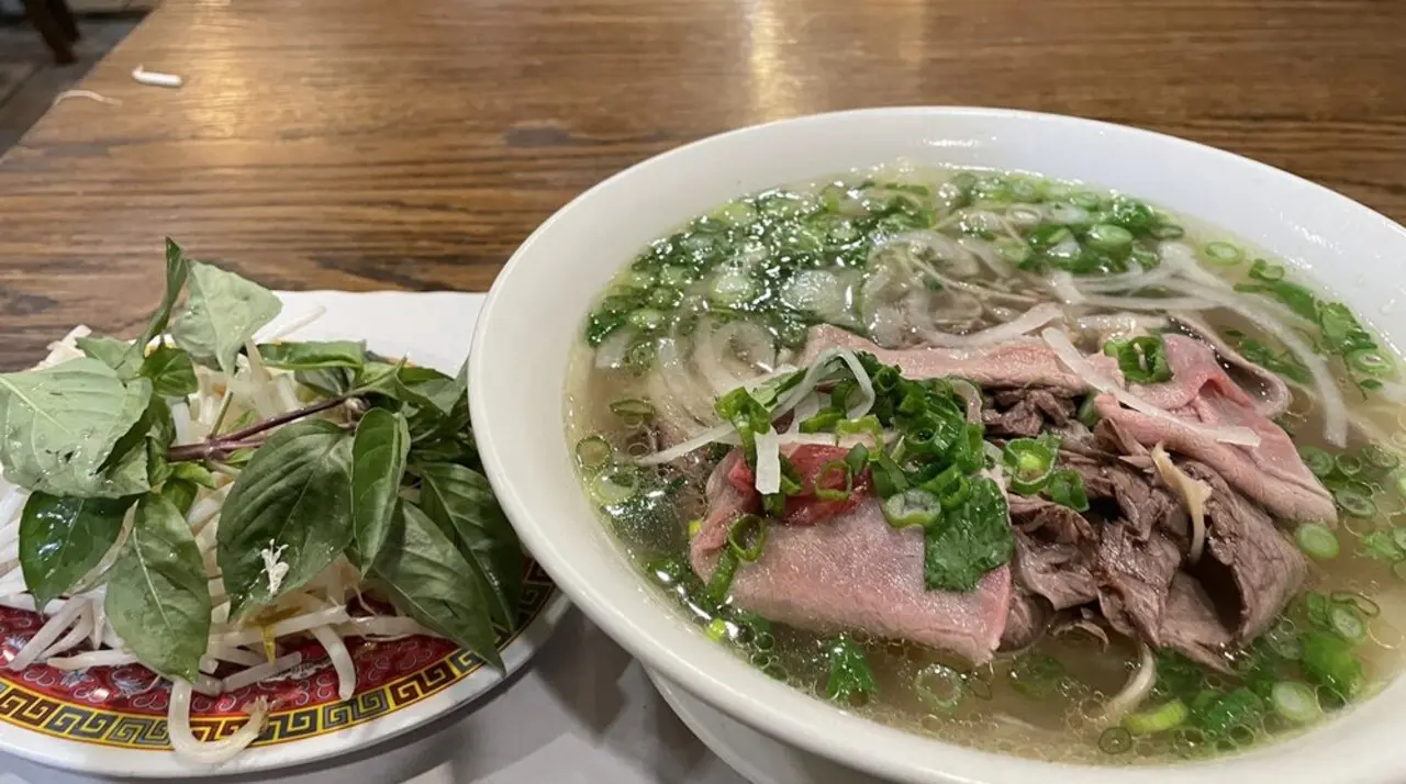 Bowl of Pho Thanh rare beef pho with bean sprouts and Thai basil on the side