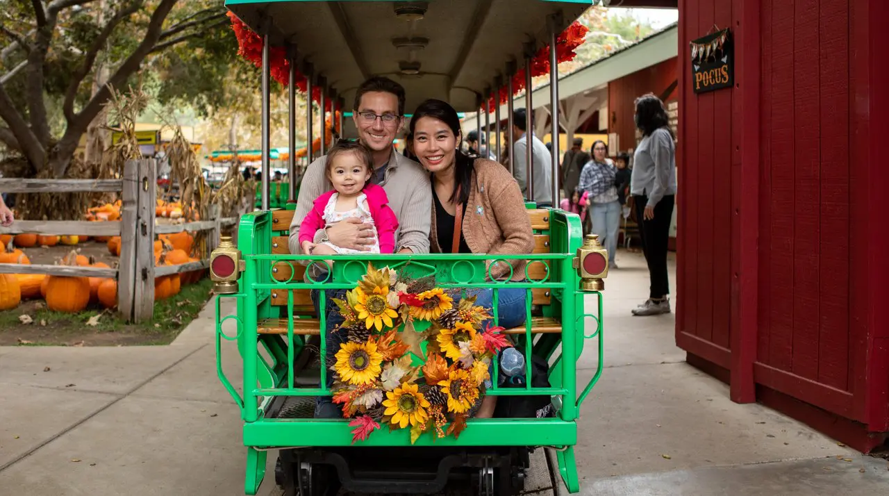 Family riding a pumpkin-decorated train car at the Irvine Park Railroad Pumpkin Patch in Orange